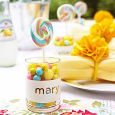 a table topped with candy and lollipops on top of white plates next to yellow flowers