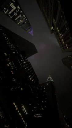 the lights of skyscrapers shine brightly in the dark night sky, as seen from below