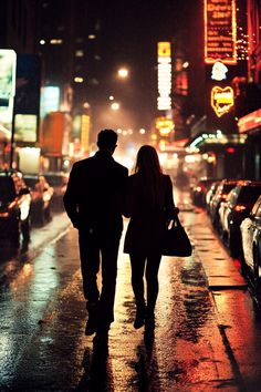 a man and woman walking down the street in the rain at night with neon lights