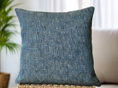 a blue pillow sitting on top of a white couch next to a potted plant