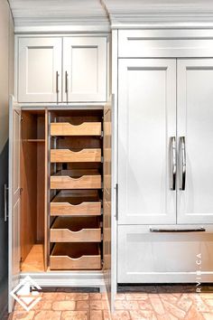 a kitchen with white cabinets and drawers in the center, an open pantry door is visible