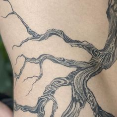 the back of a woman's leg with a tree tattoo on her lower body