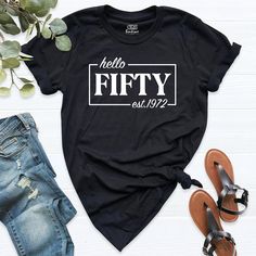 a black t - shirt with the words hello fifty est 1932 on it next to some shoes