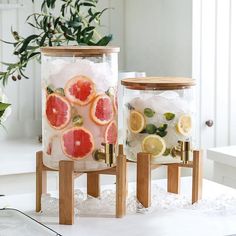 two glass jars filled with watermelon, lemon and lime slices on wooden stands