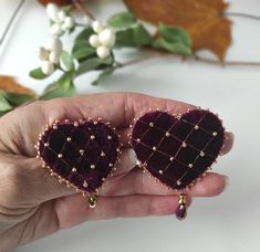 two heart shaped brooches are held in someone's hand