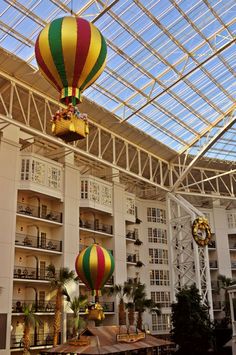 two hot air balloons are suspended from the ceiling in front of a large hotel lobby