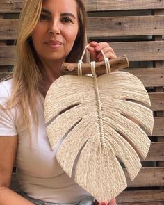 a woman holding up a large rattan palm leaf purse in front of her face