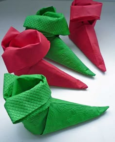 four origami napkins are arranged in the shape of cones with bows on them