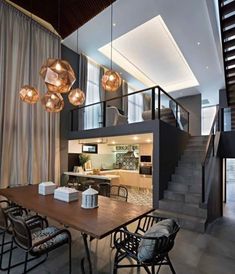 a dining room table with chairs and lights hanging from it's ceiling in front of a staircase