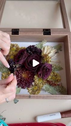 someone is making a flower arrangement out of flowers in a wooden box with scissors and glue