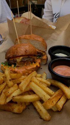 a hamburger and fries with dipping sauce on the side