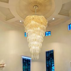 a large chandelier hanging from the ceiling in a room with two windows on both sides