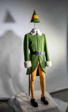 a green and yellow costume on display in front of a white backdrop with an orange hat