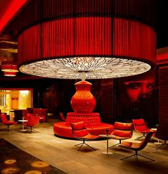 the lobby is decorated with red chairs and round chandelier, along with art work on the walls