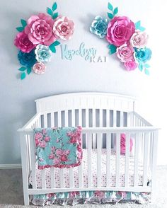 a white crib with pink and blue flowers on the wall