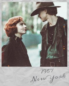 a man and woman standing next to each other in front of a white sheet with the words new york written on it