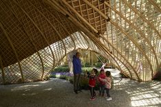 two adults and three children standing in front of a building made out of bamboo sticks