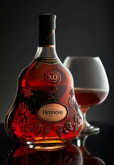 a bottle of hennesy with two glasses behind it