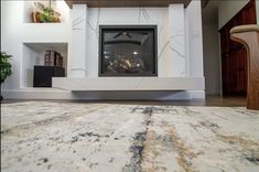 a fireplace in a living room with a large rug on the floor next to it