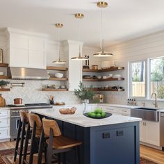 a kitchen with white cabinets and blue island in front of the countertop, surrounded by wooden stools