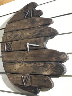 a large wooden clock mounted to the side of a building with roman numerals