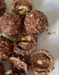 chocolate covered donuts with walnuts and nuts in the middle on a white plate