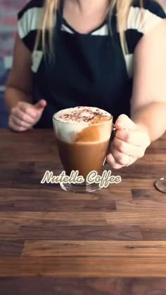 a woman sitting at a table with a cup of coffee