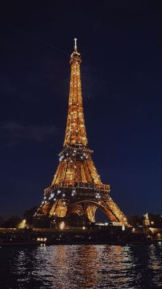 the eiffel tower lit up at night with lights reflecting in the water below