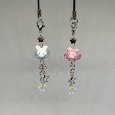 two key chains with charms attached to them on a gray background, one has a pig and the other is a fish