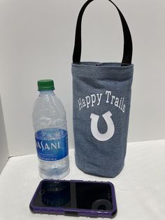 a cell phone, water bottle and tote bag sitting on a table