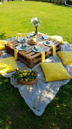 a picnic table set up with lemons and plates on it in the middle of a grassy area