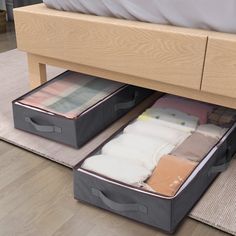 an open suitcase sitting on top of a bed next to two boxes with folded clothes in them