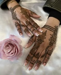 two hands with henna tattoos and a rose