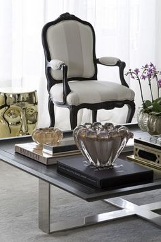 a living room with a glass table and chair in front of a large window that has white curtains on the windowsill