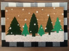 a door mat with trees on it and snowing in the background, sitting on a wooden floor