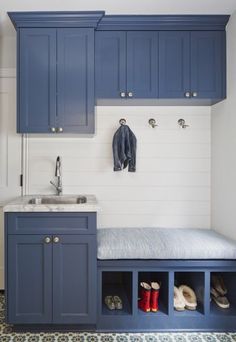 a kitchen with blue cabinets and a white counter top next to a sink under a hanging coat rack