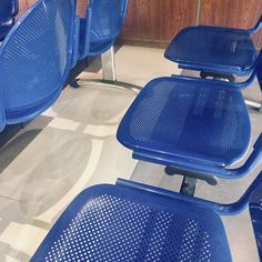 several blue plastic chairs sitting on top of a tiled floor