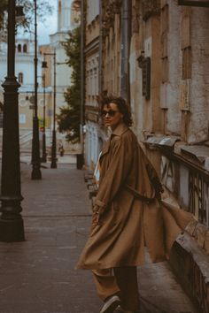 a man in a trench coat is walking down the street