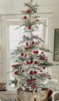 a small christmas tree in a bucket with ornaments on it and ribbon around the base