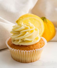 there is a cupcake with frosting and a lemon on the top, next to an orange