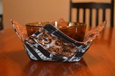 an origami bowl sitting on top of a wooden table next to a black chair