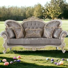 an old fashioned couch sitting in the middle of some grass with colored eggs around it