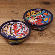 two colorful bowls sitting on top of a wooden table