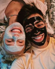 two people are laying down with their faces covered in black and white facial maskes