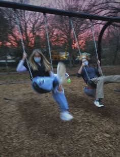 two children swinging on swings in a park