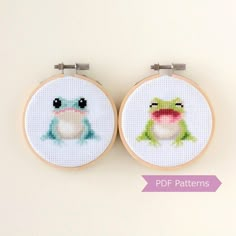 two cross - stitch frog pictures are hanging on the wall