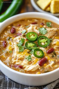 a white bowl filled with chicken chili soup and topped with jalapeno peppers