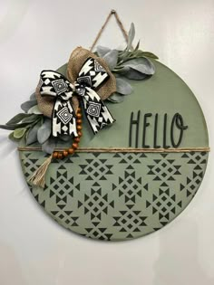 a sign that says hello hanging on the side of a wall with leaves and beads