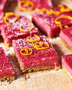 red desserts are arranged on a table with powdered sugar and orange peels