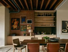 a dining room table surrounded by chairs and shelves